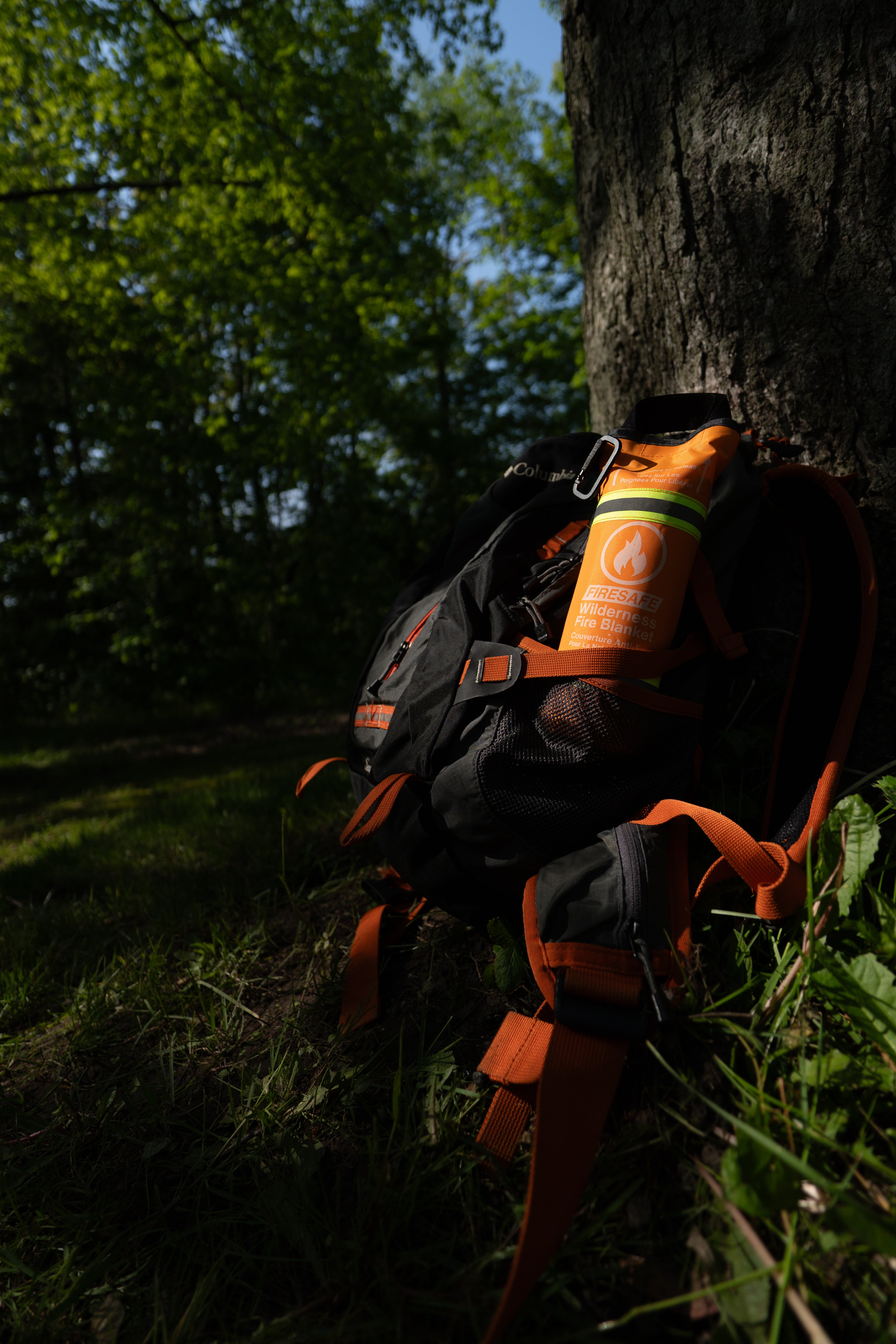 FireSafe Wilderness Fire Blanket tucked into a hiking backpack water bottle pocket in a sunlit forest